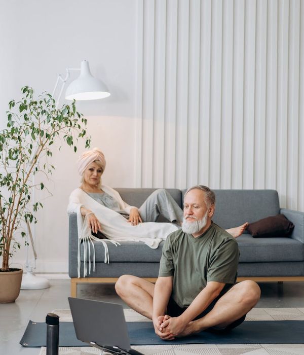 Person performing a gentle stretching pose in a calm, minimalist room.